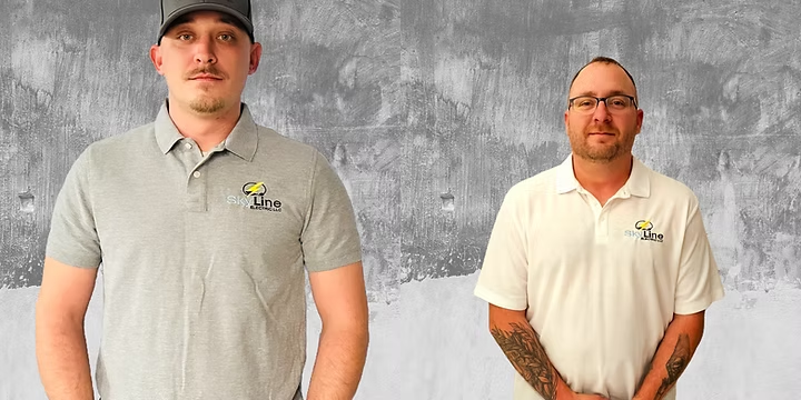 Two men stand against a gray textured background wearing shirts with a logo and text that reads 